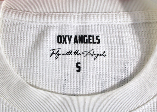 Close-up of a white garment with 'OXY ANGELS' branding and text.