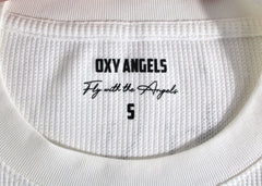 Close-up of a white garment with 'OXY ANGELS' branding and text.