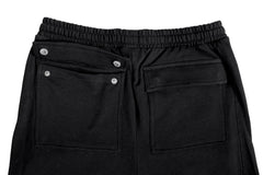 Black pants with button details on a light gray background