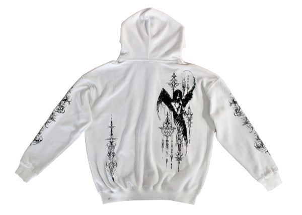 White hoodie with black graphic designs on a gray surface