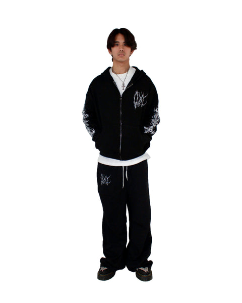 Person wearing a black hoodie and pants with white designs on a white background