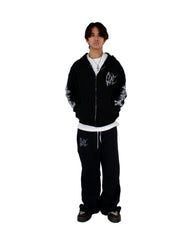 Person wearing a black hoodie and pants with white designs on a white background