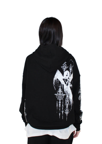 Person wearing a black hoodie with a white graphic design on the back against a plain background