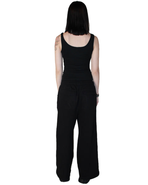Person wearing a black sleeveless top and wide-leg pants on a white background