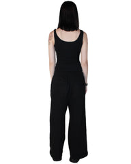 Person wearing a black sleeveless top and wide-leg pants on a white background