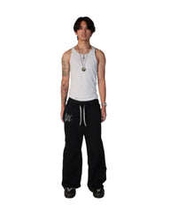 Person wearing a white tank top and black pants on a white background