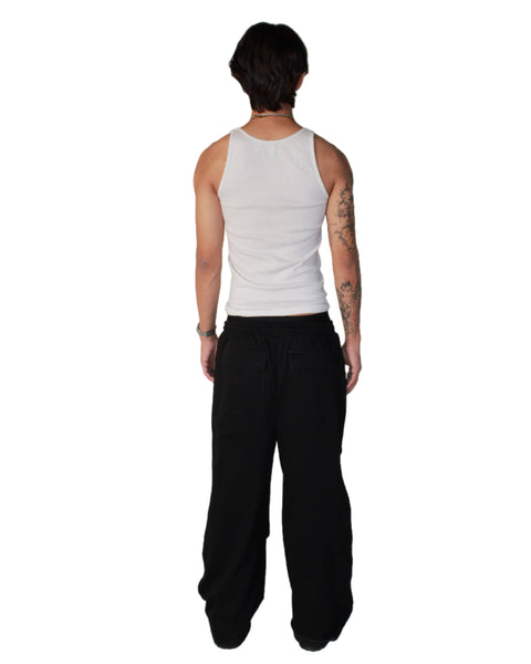 Person wearing a white tank top and black pants on a white background
