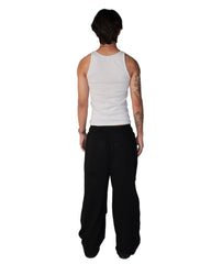 Person wearing a white tank top and black pants on a white background