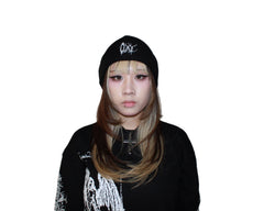 Person wearing a black beanie and black outfit with white designs on a white background