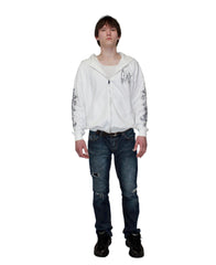 Person wearing a white hoodie with text and graphics, dark jeans, and black shoes on a plain background