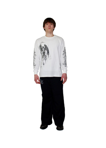 Person wearing a white long-sleeve shirt with black graphics and black pants on a white background