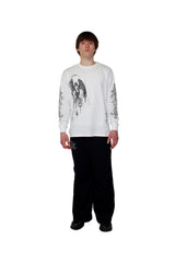 Person wearing a white long-sleeve shirt with black graphics and black pants on a white background