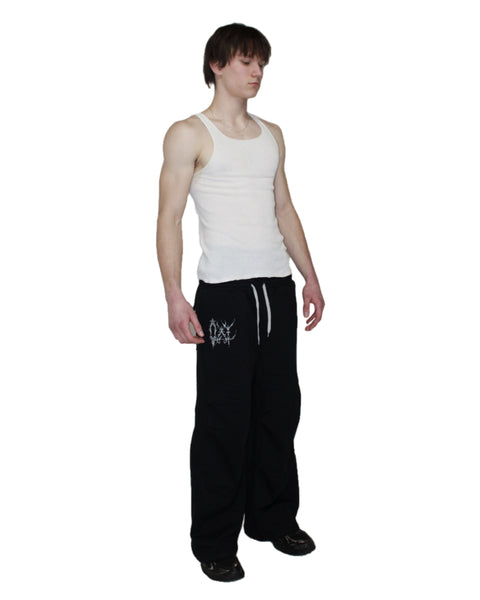Person wearing a white tank top and black pants on a white background