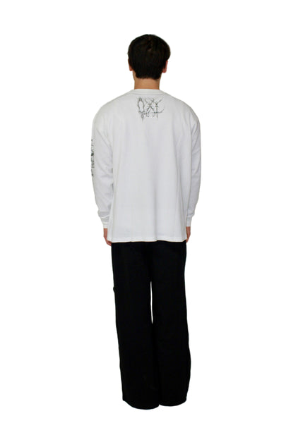Person wearing a white long-sleeve shirt with black text and black pants on a plain background