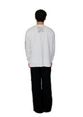 Person wearing a white long-sleeve shirt with black text and black pants on a plain background