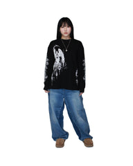 Person wearing a black long-sleeve shirt with white graphic design and blue jeans on a white background