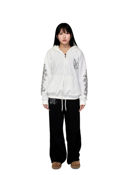 Person wearing a white hoodie with black text and graphics on a plain background