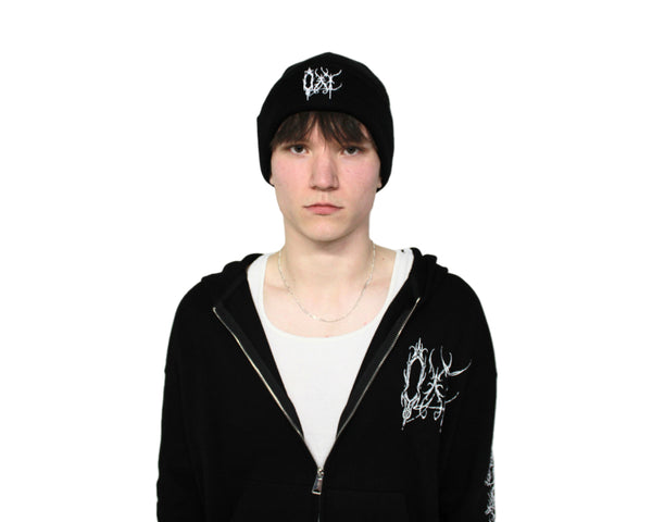 Person wearing a black hoodie and cap with white designs on a light gray background
