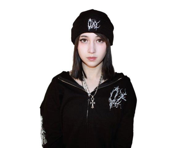 Person wearing a black hoodie and cap with white designs on a plain background