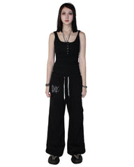 Person wearing a black sleeveless top and wide-leg pants on a white background