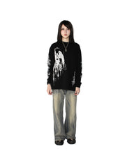 Person wearing a black sweater with white designs and light gray pants on a white background