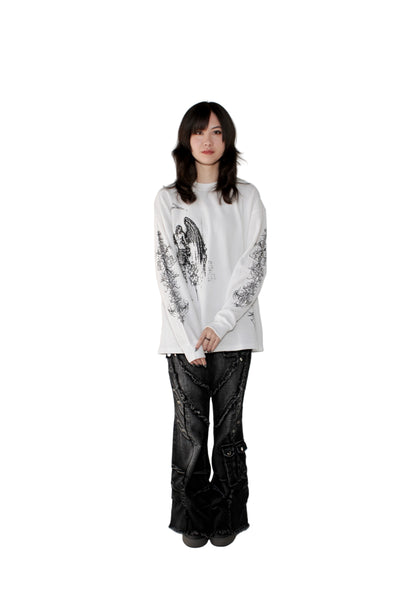 Person wearing a white long-sleeve shirt with black patterns and black pants on a plain background